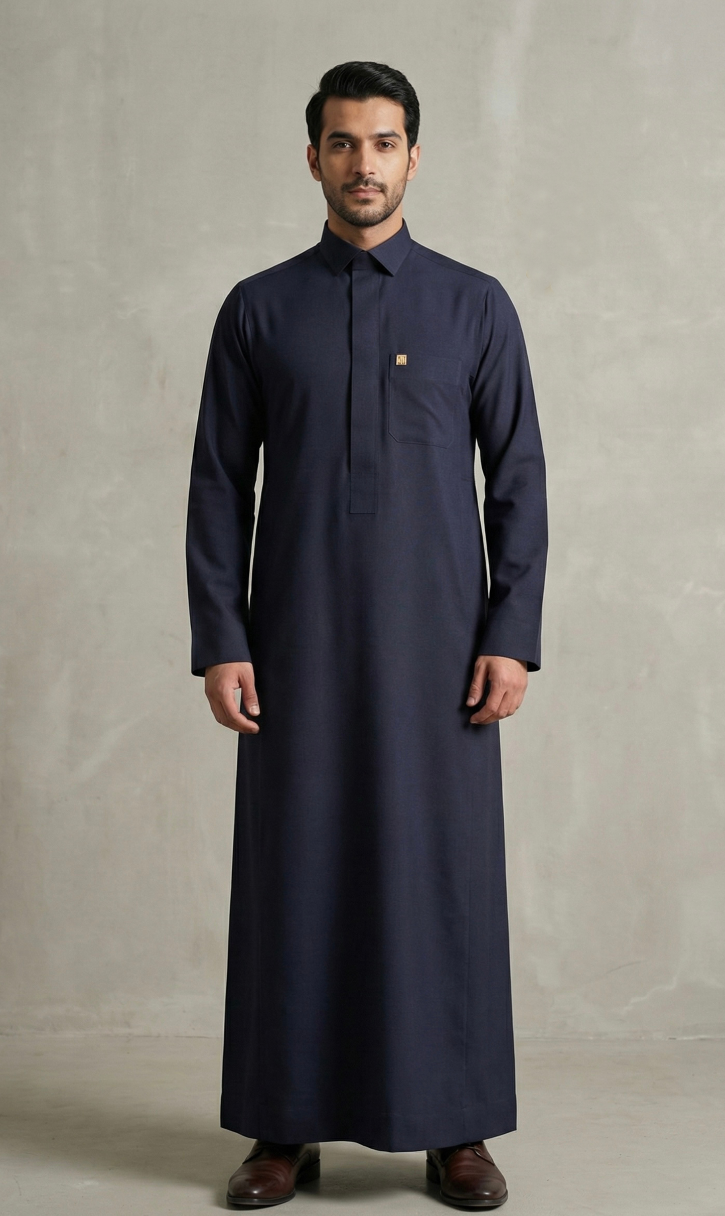 Man wearing a long dark blue garment against a plain background